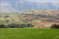 Some walkers in front of background hills